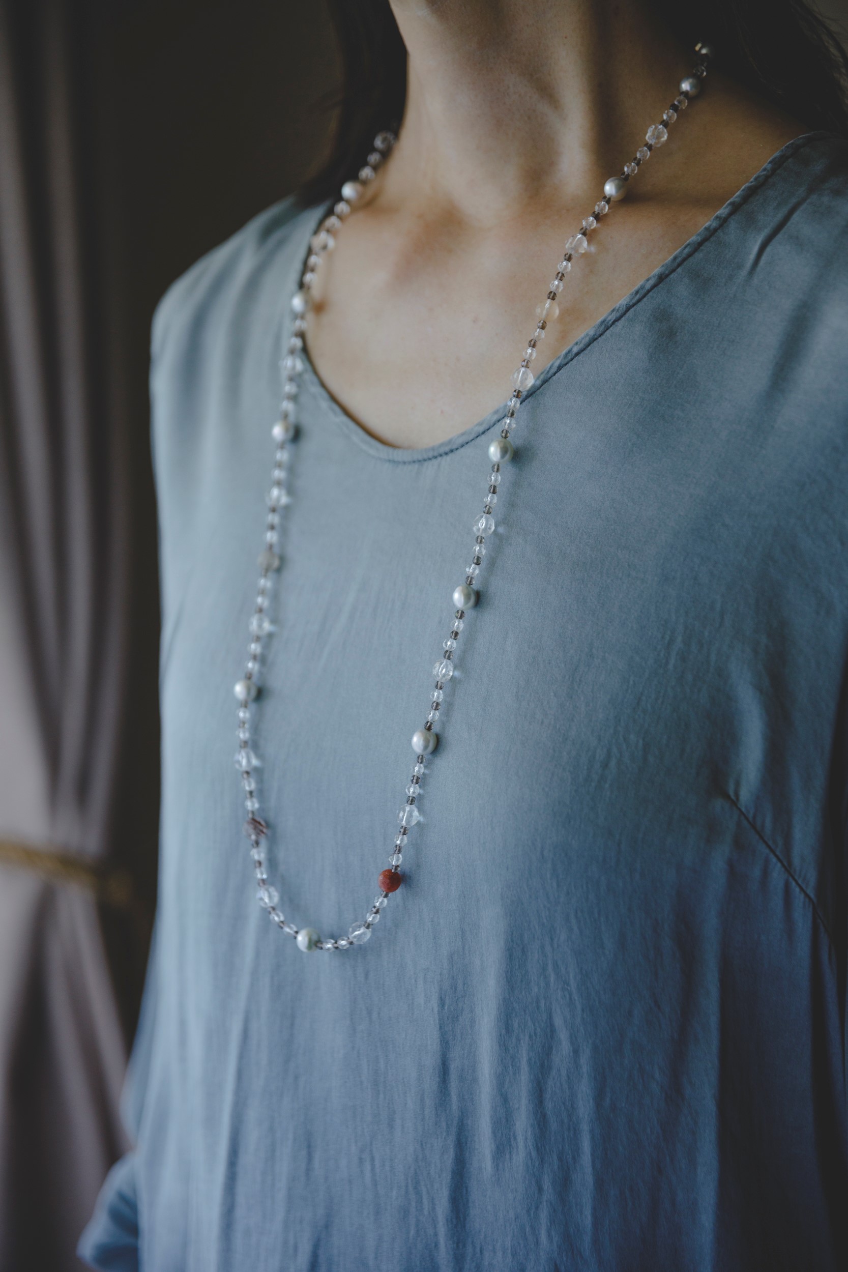 Long pearl necklace worn with a pale blue dress